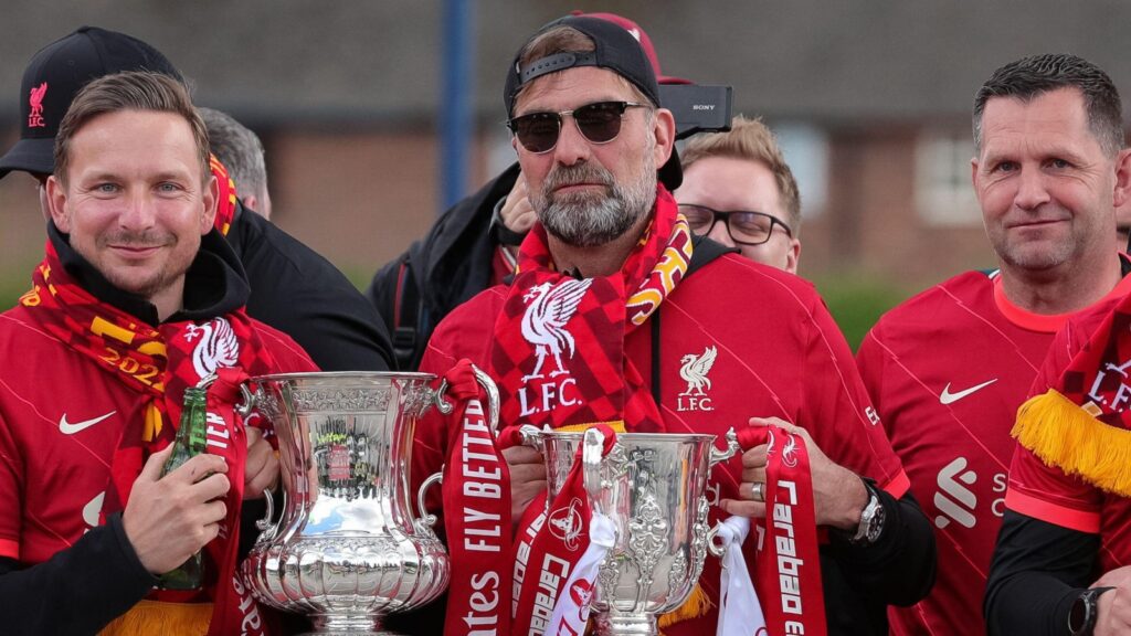 Liverpool staff including Jurgen Klopp pose with the FA Cup and Carabao Cup